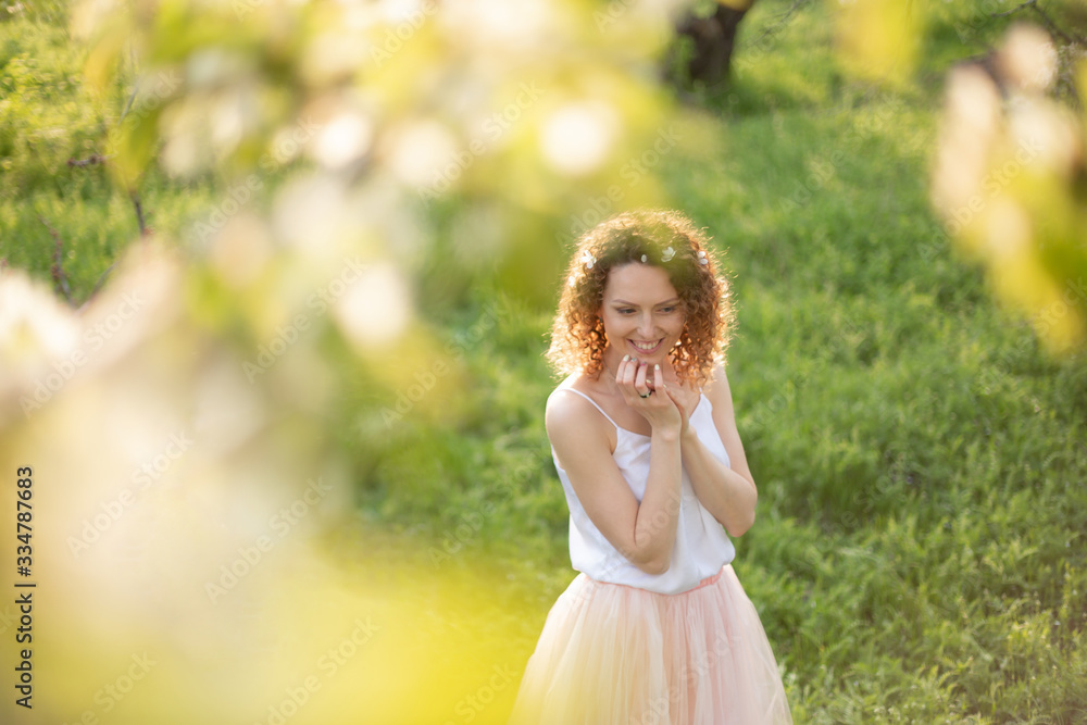Young attractive girl walks in spring green park enjoying flowering nature Young attractive girl walks in spring green park enjoying flowering nature