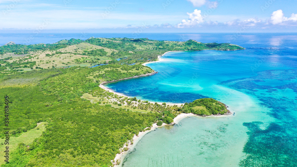 A lagoon with a coral reef and a white sandy beach, aerial drone. The coast of a tropical island. Caramoan Islands, Philippines. Summer and travel vacation concept.