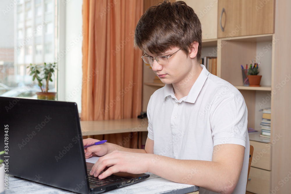 Student in glasses learning at home using laptop. Home school, online education, home education, quarantine concept Student in glasses learning at home using laptop. Home school, online education, home education, quarantine concept