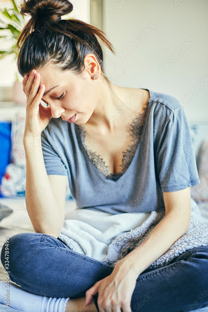 Sick woman sitting in bed with flu and huge headache. Sick woman sitting in bed with flu and huge headache.