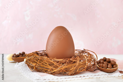 Nest with tasty chocolate Easter egg on table photo