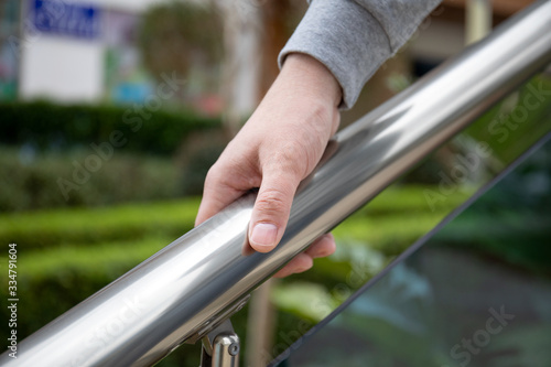 male hand holds metal handrail in a public place