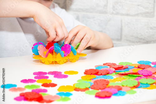 A child in bright clothes plays a developmental game with multi-colored circles. Early childhood development. Home leisure.