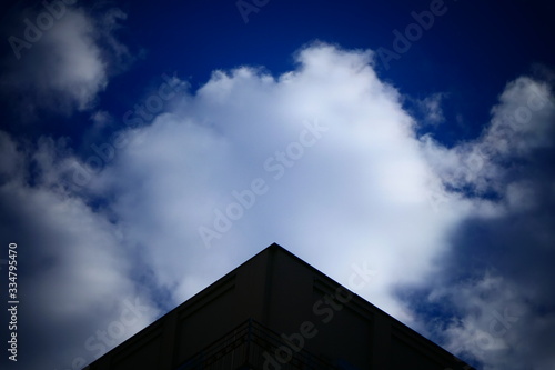 silhouette of building roof in form of triangle and blue sky and white clouds