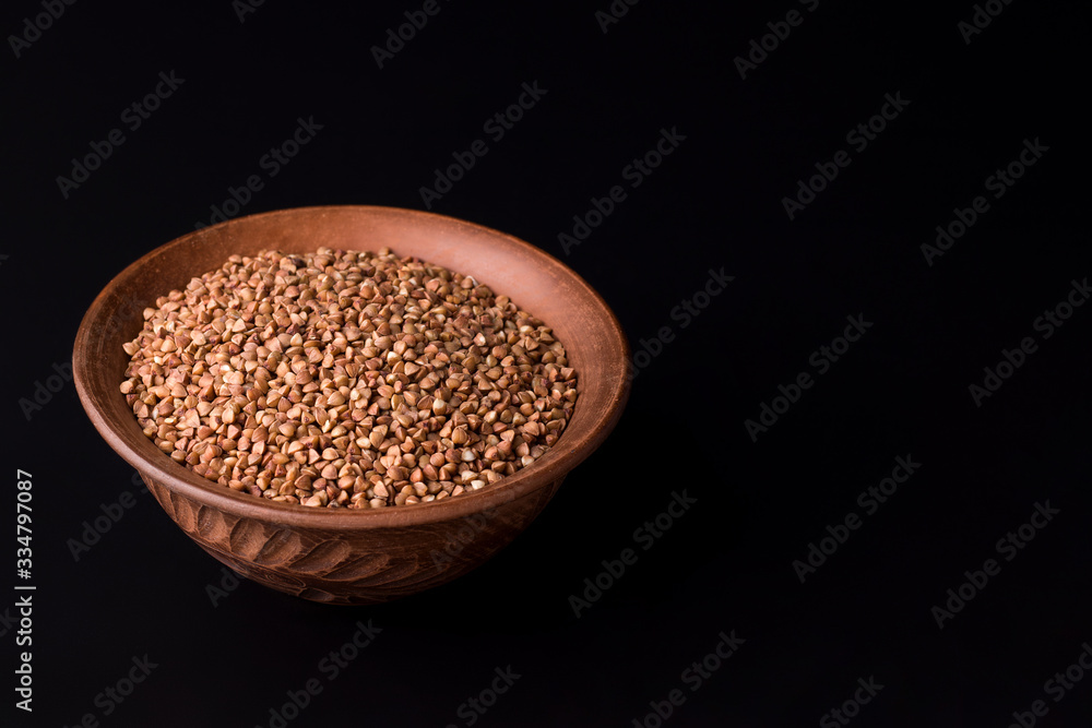 buckwheat in a clay bowl on a black background. copy space buckwheat in a clay bowl on a black background. copy space