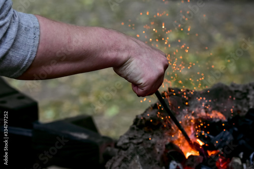 The working hand of a blacksmith tedding coals in an iron forge close up
