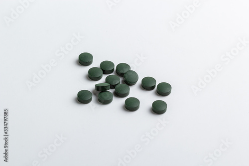 Green pills isolated on a white background. Spirulina tablets.