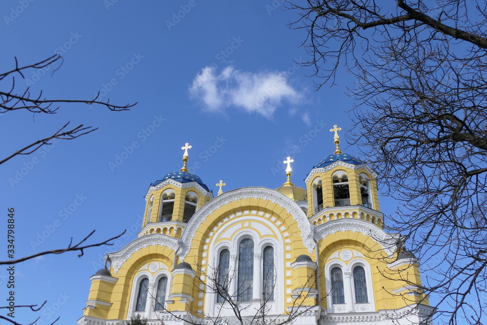 Orthodox church with yellow walls, blue domes and golden crosses