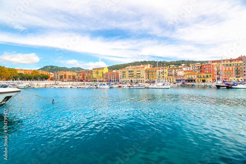 Boats in the marina and cafes and shops along the sea at the colorful old port of the Mediterranean city of Nice, France, along the French Riviera.