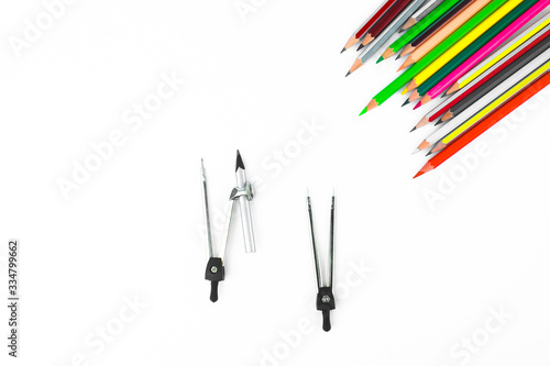 A row of different colored pencil crayons pointing at two pencil compass