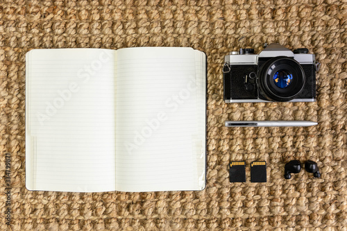 notebook, camera, memory cards, pen and headphones on an antique wooden table. photography concept