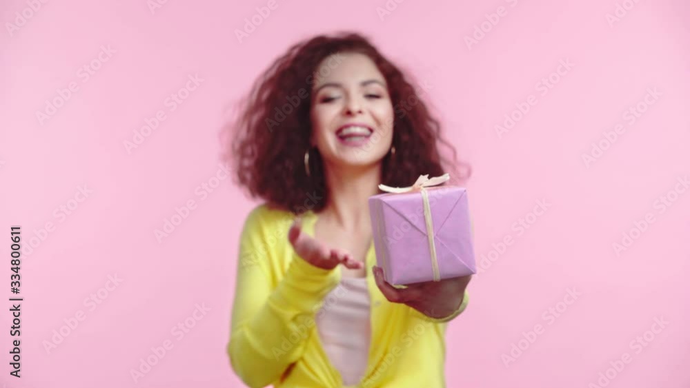 happy girl pointing with finger at gift box isolated on pink happy girl pointing with finger at gift box isolated on pink