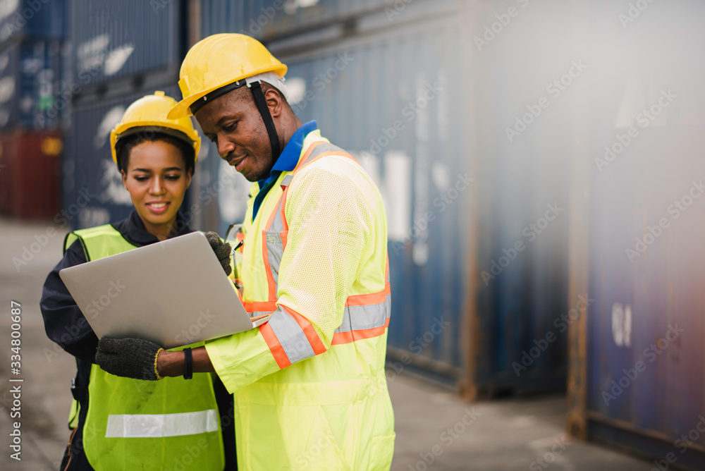 Young African american men and woman worker Check and control loading  freight Containers by use computer laptop at commercial shipping dock  felling happy. Cargo freight ship import export concept Photos | Adobe