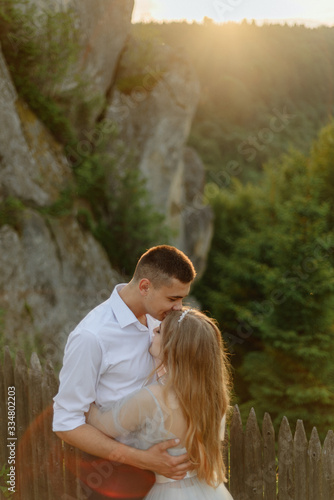 Photoshoot of a couple in love in the mountains. The girl is dressed like a bride in a wedding dress.