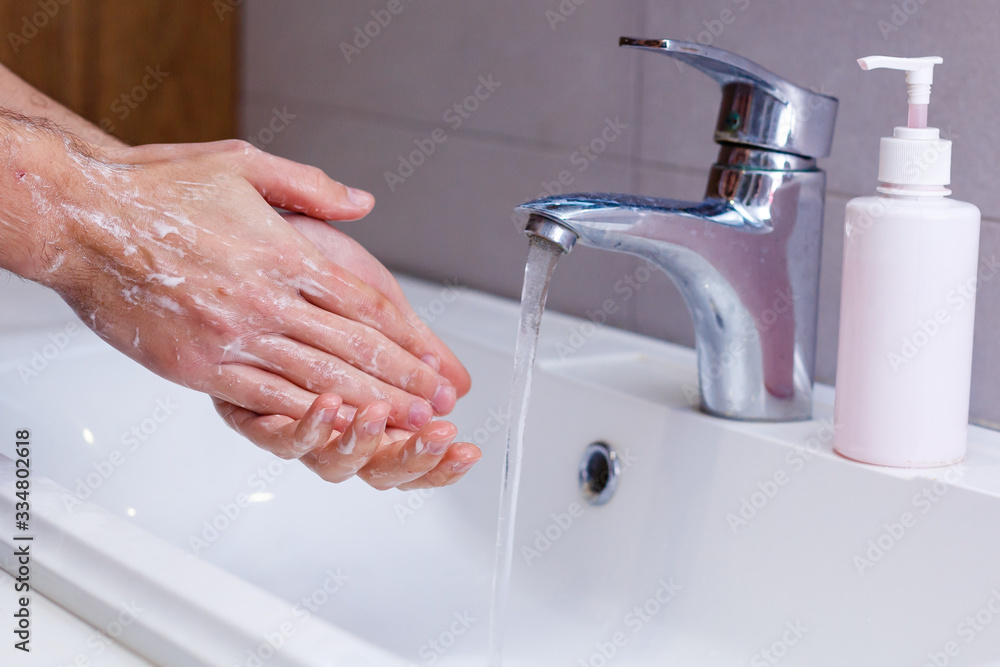 Man washing his hands in running water, in a public toilet. Man washing his hands in running water, in a public toilet.