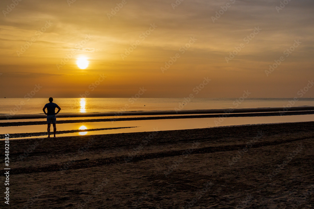 Silhouette of an unidentified young man enjoying summer at an Adriatic coast sunrise, sandy Senigallia beach, Province of Ancona, Marche, Italy