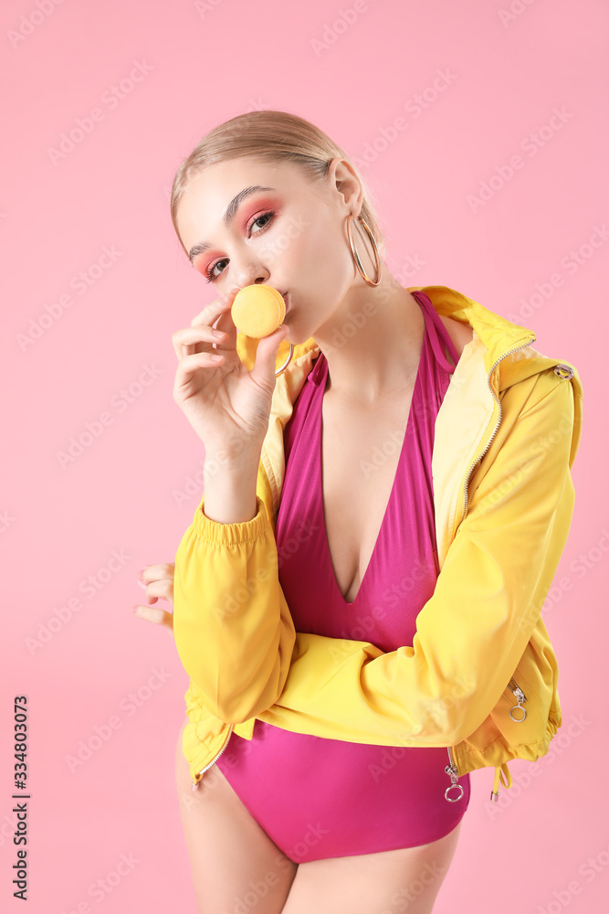Beautiful fashionable woman with macaron on color background Beautiful fashionable woman with macaron on color background