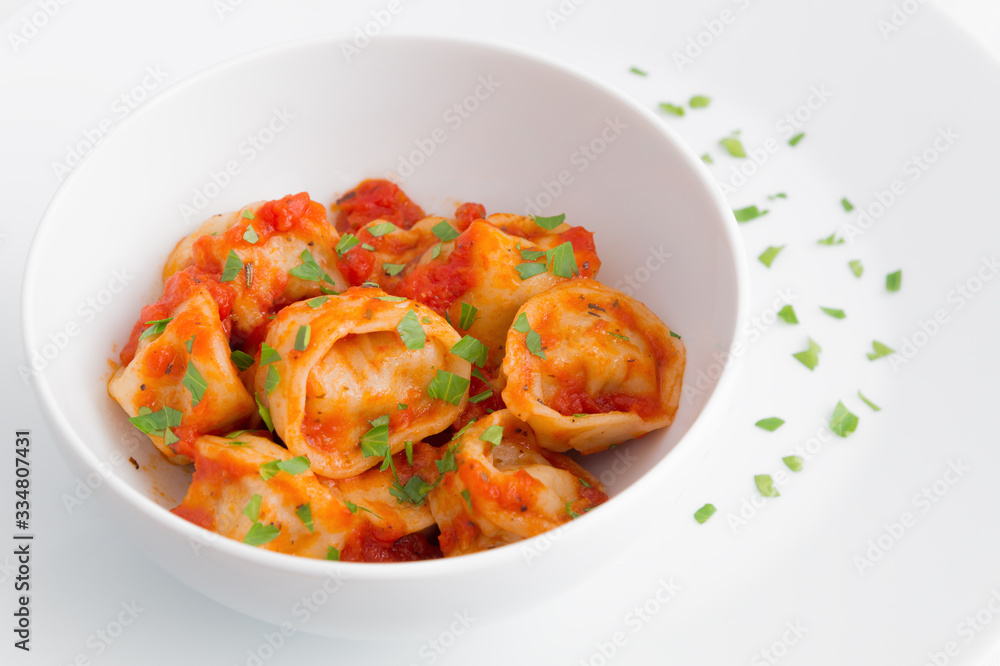 a bowl of ravioli with tomato sauce on a plate decorated with parsley a bowl of ravioli with tomato sauce on a plate decorated with parsley