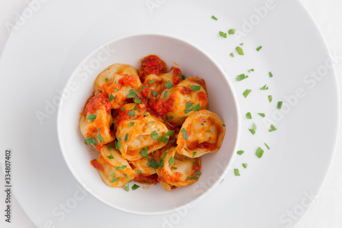 ravioli with tomato sauce on a plate decorated with parsley 