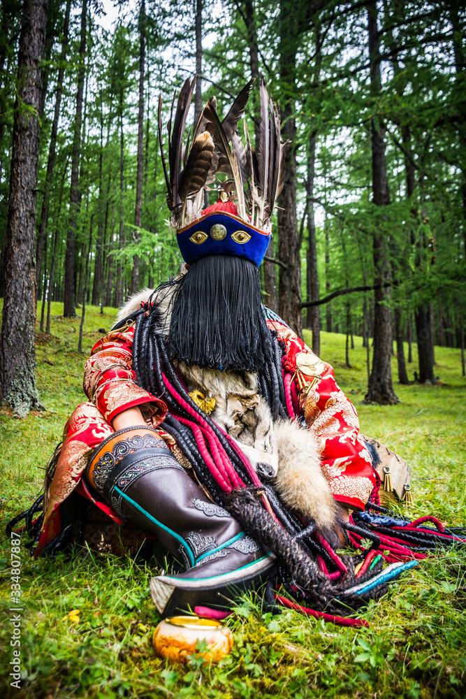 Portrait of a Mongolian Shaman wearing cerimonial clothes in a pine forest close to Ulanbataar, Mongolia.