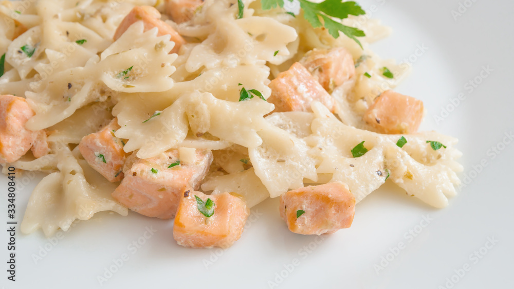 fried salmon chops and farfalle pasta with cream sauce decorated with parsley fried salmon chops and farfalle pasta with cream sauce decorated with parsley