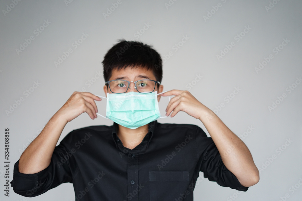 The man doing wearing face hygienic mask for prevention global covid-19 virus pandemic. The corona-virus from Wuhan is dangerous. Use his hands pull mask into face. The man doing wearing face hygienic mask for prevention global covid-19 virus pandemic. The corona-virus from Wuhan is dangerous. Use his hands pull mask into face.