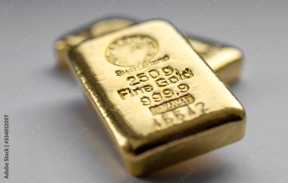 Two gold bullions weighing 250 grams each on a grey background. Selective focus. Two gold bullions weighing 250 grams each on a grey background. Selective focus.