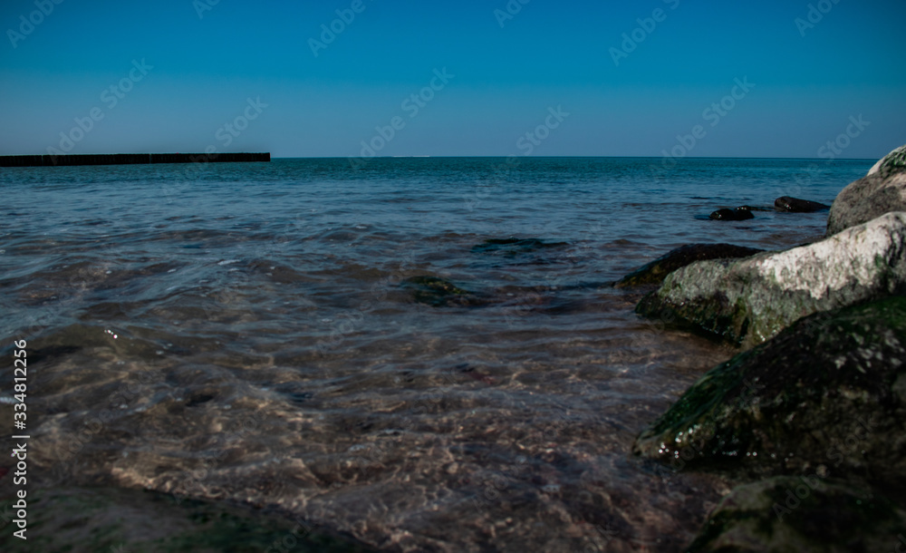 view of the rocky beach of the sea or ocean in sunny weather with clear blue sky