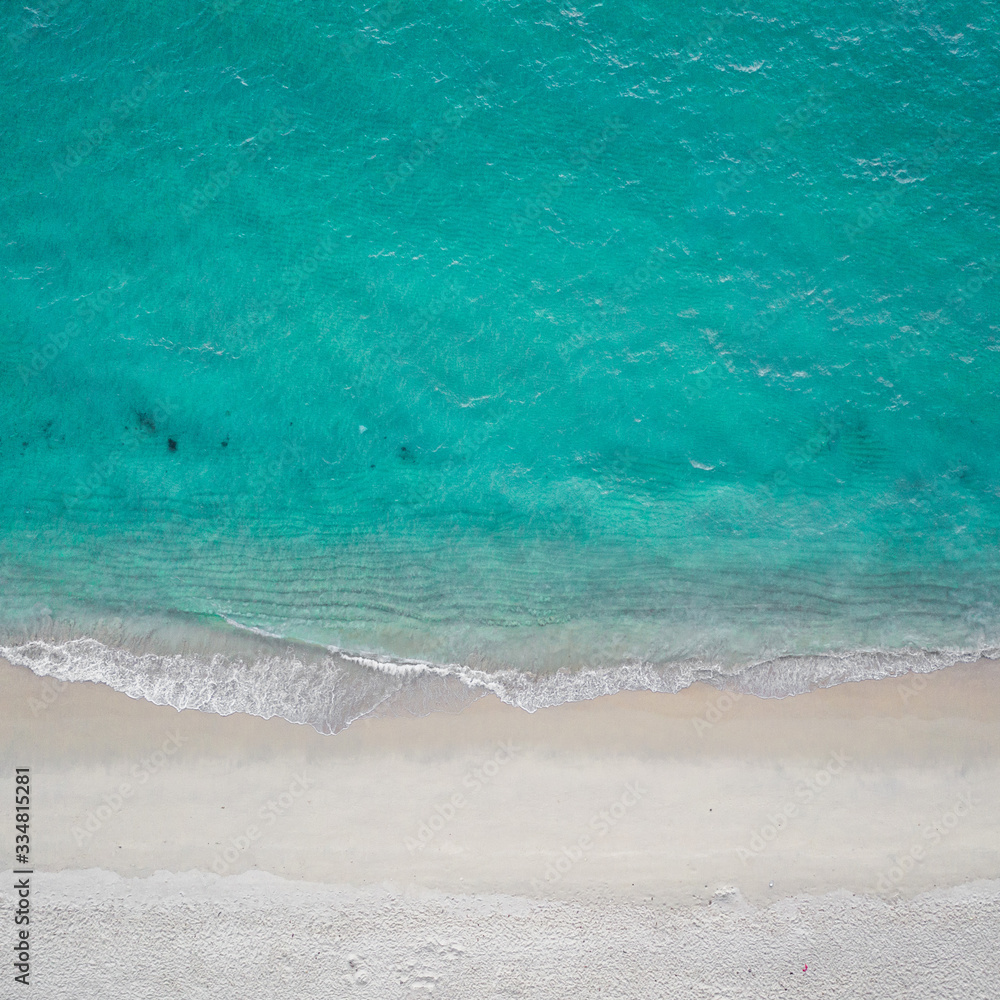 Aerial drone top view of sea waves crashing against the sandy empty beach