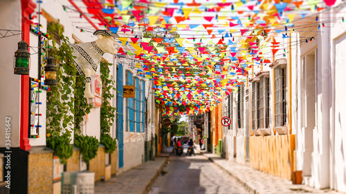 Beautiful and colorful colombian street with pennant flags decorating the houses, big statue in the shape of a cow wearing a typical Colombian hat. Colorful abundant fair flags on beautiful day.