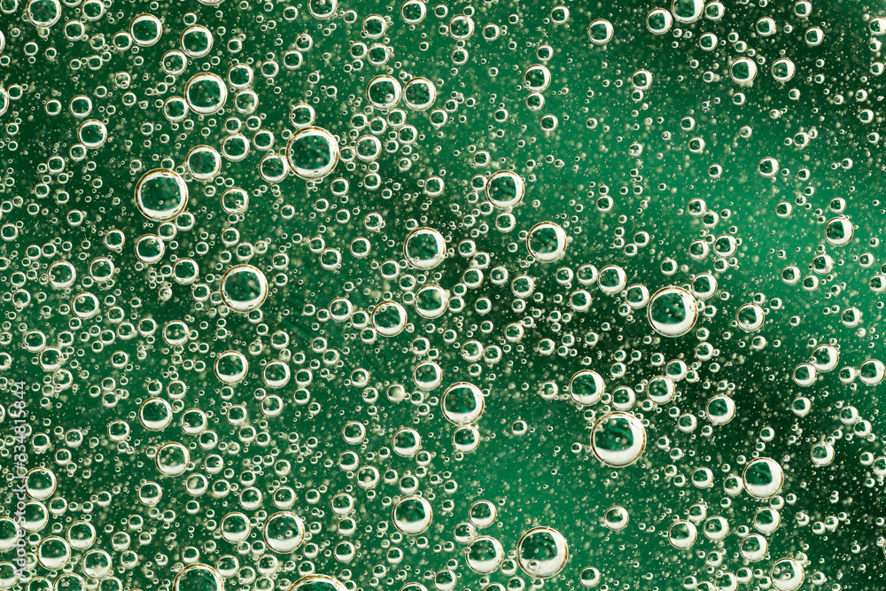 Abstract green background with oil circles . Bubbles of water close up . 