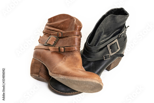 Mismatched old brown and back leather boots isolated on a white background.