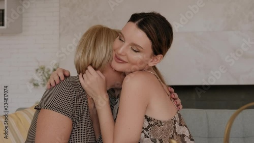 Portrait of old mother and mature daughter hugging at home. Happy senior mother and adult daughter embracing with love on sofa.