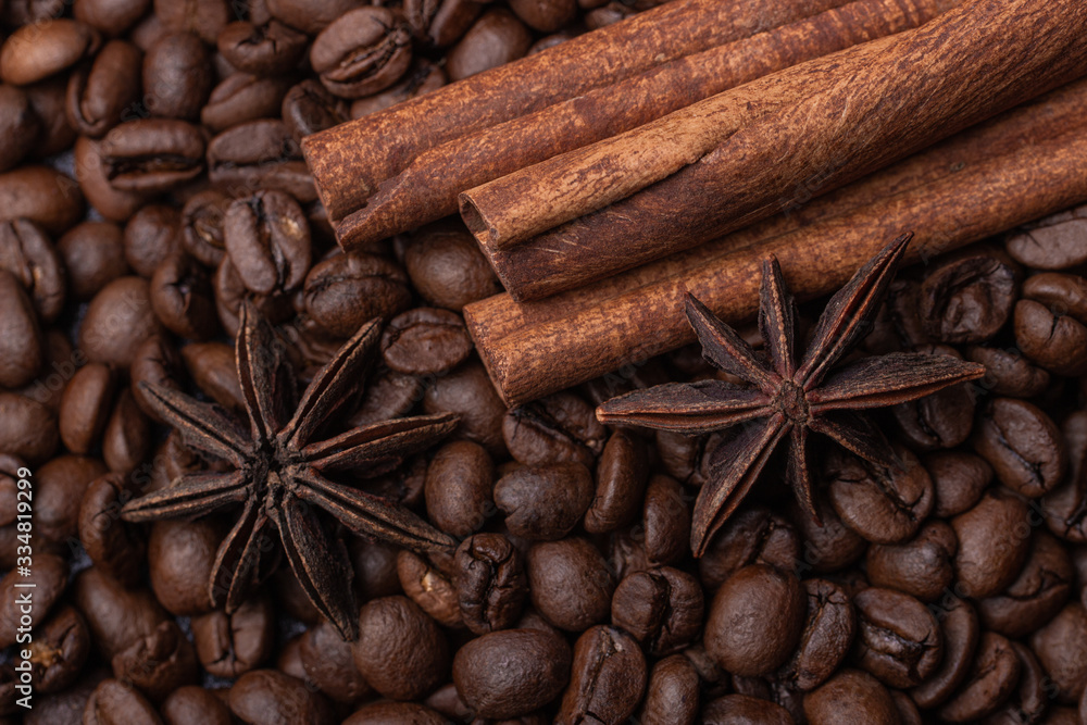 Fototapeta Three cinnamon sticks and a star anise against the background of coffee beans