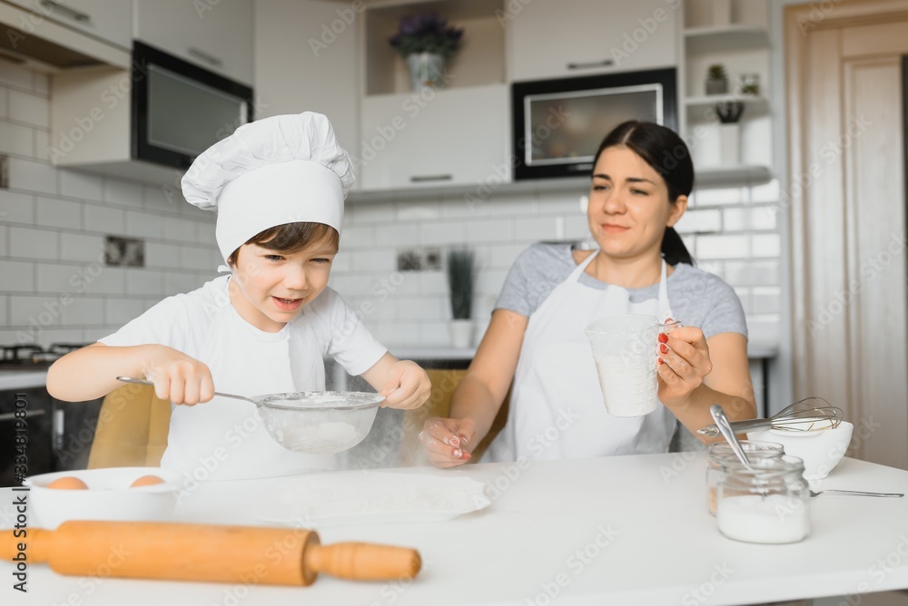 Child helping mother make cookies in modern kitchen