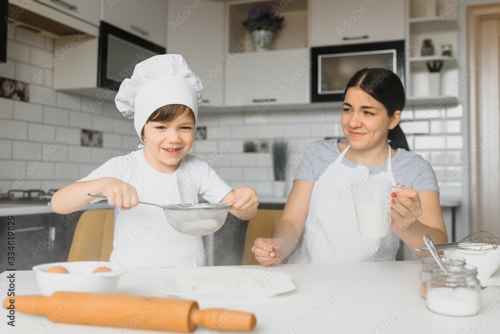 Young mother and her little son baking cookies together at home kitchen Young mother and her little son baking cookies together at home kitchen