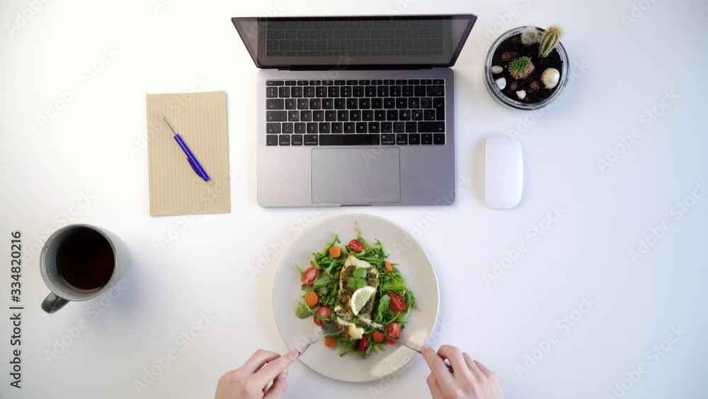 Top view of male eating healthy salad at work place next to laptop Top view of male eating healthy salad at work place next to laptop