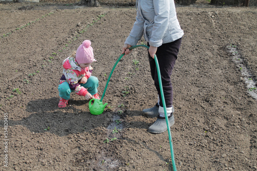 happy childhood. little girl with watering can in the garden