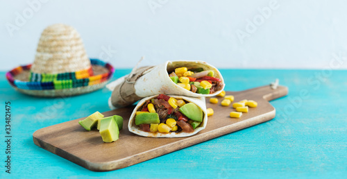 Mexican burritos on a kitchen table on a blue background. Mexican cuisine concept. Copy space.