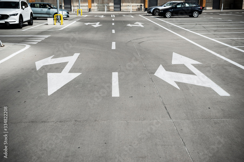 White arrow signs on the grey concrete surface of the road/parking