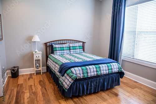 Obraz na plátne Light gray teenage boy bedroom with a wood bed and plaid bedspread and curtains