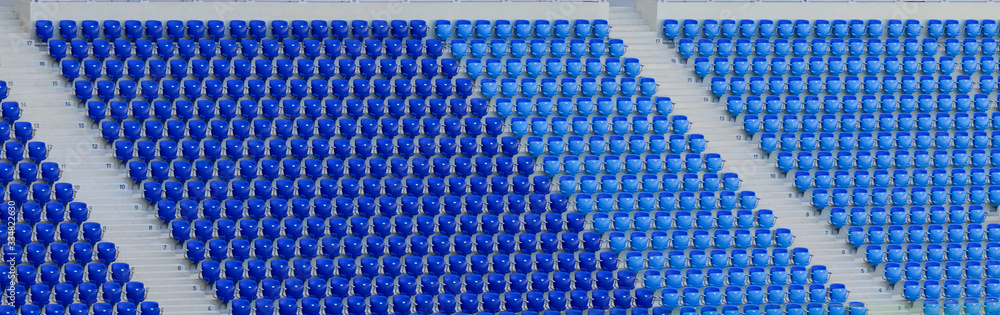 Naklejka premium Empty blue and dark-blue seats in the stadium before the match