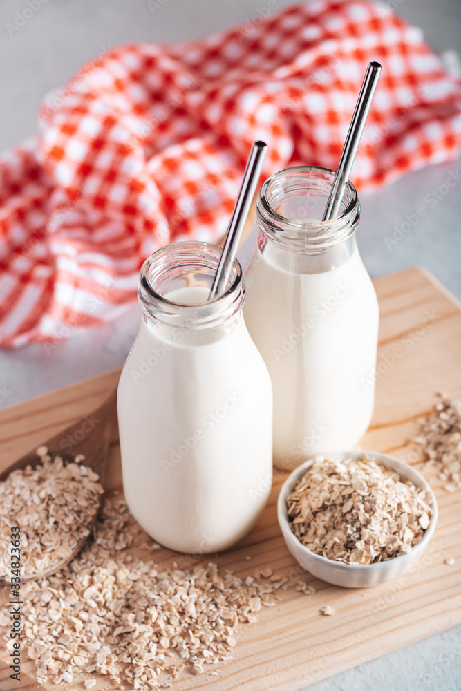Non dairy oat milk in glass jars with reusable metal straws. Healthy vegan milk alternative still life, copy space. Substitute for traditional cow milk with oat flakes, healthy lifestyle concept Non dairy oat milk in glass jars with reusable metal straws. Healthy vegan milk alternative still life, copy space. Substitute for traditional cow milk with oat flakes, healthy lifestyle concept