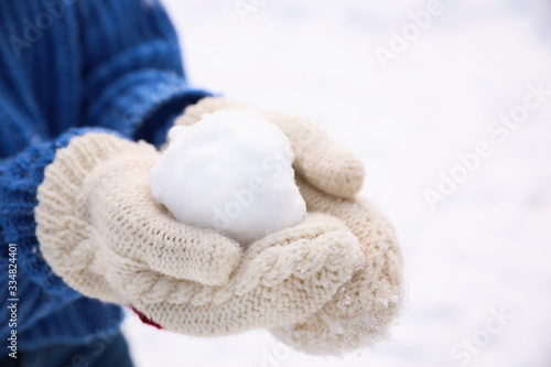 Woman with snowball outdoors, closeup. Winter vacation