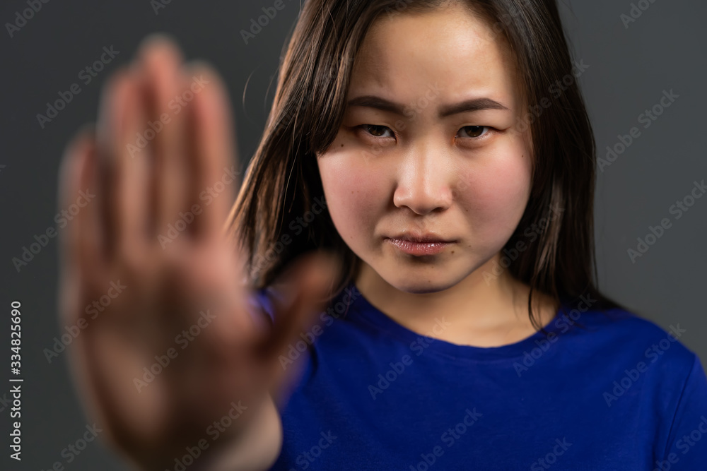 Asian woman disapproving with NO hand sign gesture. Denying, rejecting, disagree, portrait of beautiful girl or student on grey background Asian woman disapproving with NO hand sign gesture. Denying, rejecting, disagree, portrait of beautiful girl or student on grey background