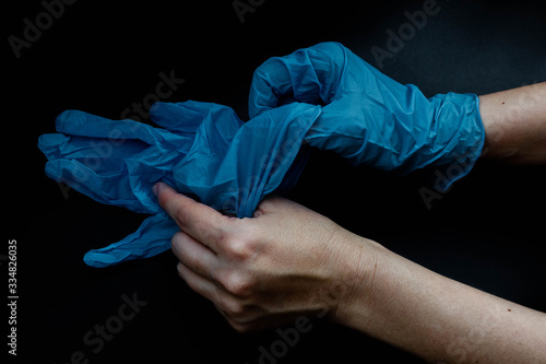 Woman in blue gloves, protection against coronavirus infection, defend you, black background