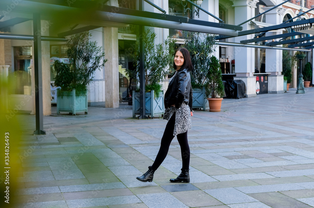 Nice, brunette woman wearing in black leather jacket walking in square city. Smile, cute girl in Batumi, Georgia. Spring time. Nice, brunette woman wearing in black leather jacket walking in square city. Smile, cute girl in Batumi, Georgia. Spring time.