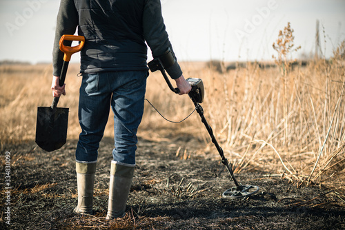 Fotografie Man with metal detector is searching for old coins in the ground.