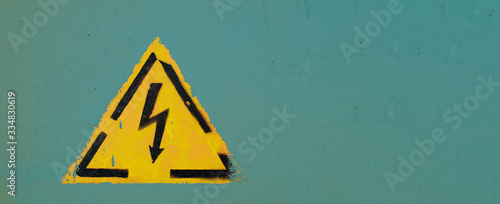 Attention sign. Electricity danger sign on a mint wall with paint drips and splatter. Horizontal shot with copy space.