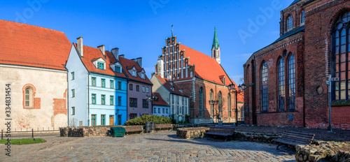 Old town square with beautiful St. John's Church and cute red roofed houses in Riga, Latvia